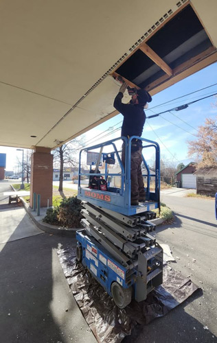 Man on lift fixing sofit of home. 