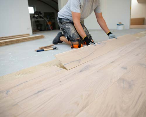 Man kneeling on the floor installing new laminate. 
