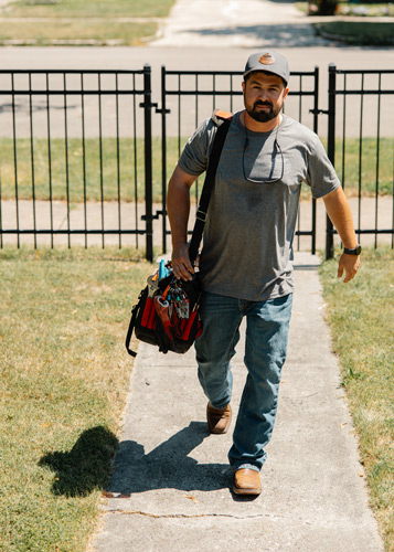 Nathan walking up to house with tool bag.