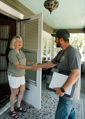 White man in late thirties with dark hair and woman in her sixties with white hair shaking hands. 